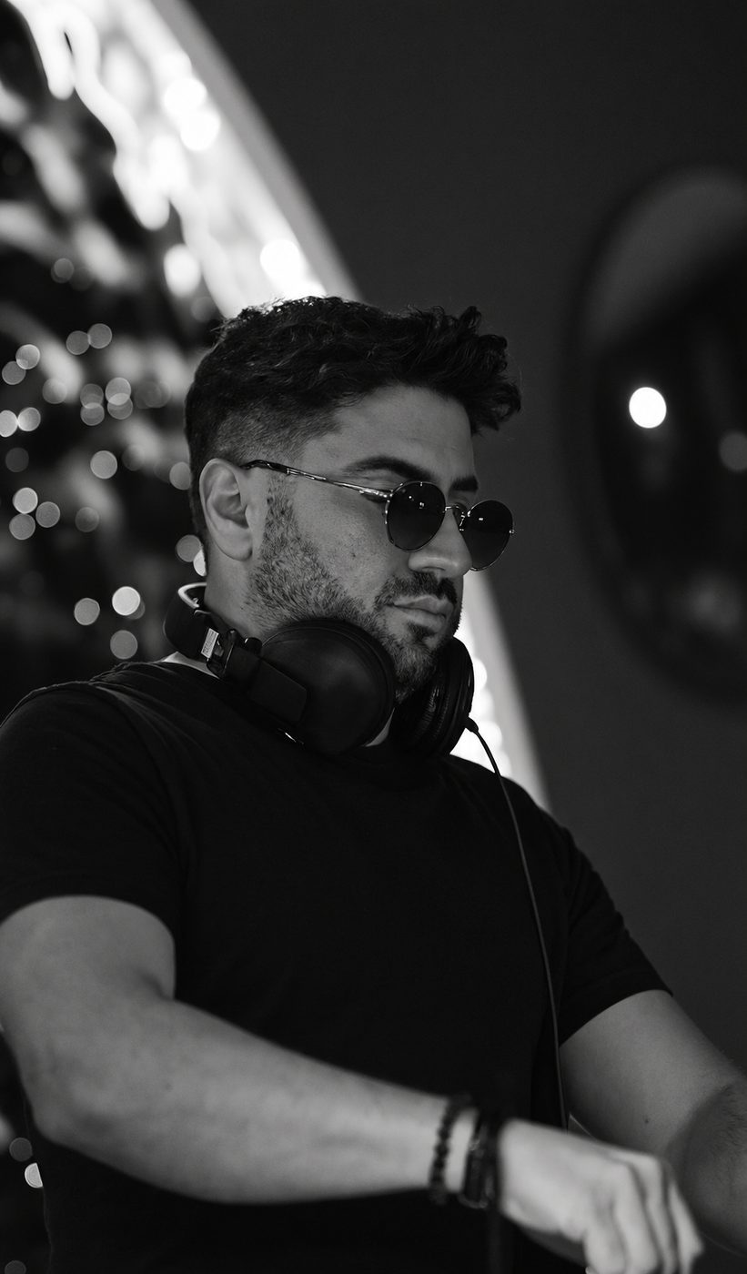 DJ Suat Doğu, kulaklık boynunda, DJ kabininde